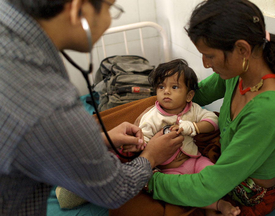 Doctor examining small child being held by her mother.