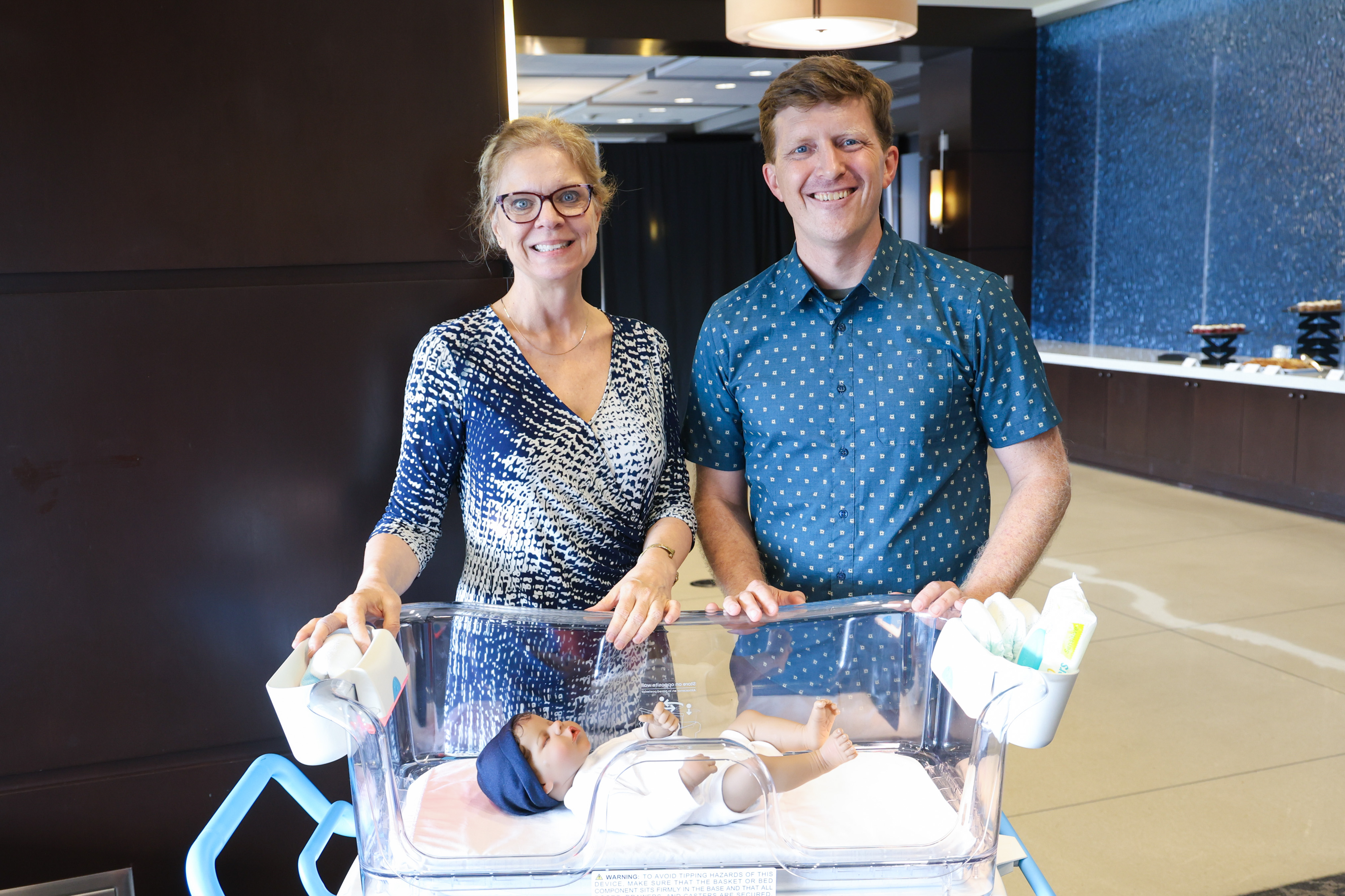 Mother and father standing in front of baby in a bassinet