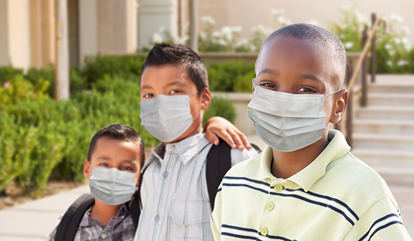 Young students on school campus wearing medical face masks.